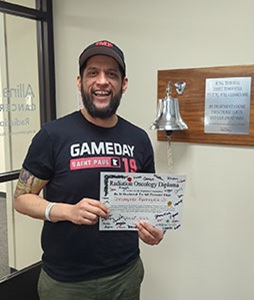 Chris Rodriguez, patient diagnosed with early-onset colorectal cancer at the age of 35, smiles in a baseball cap