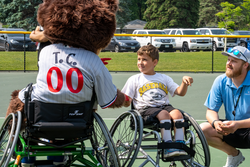volunteer and child play adaptive softball in wheelchairs