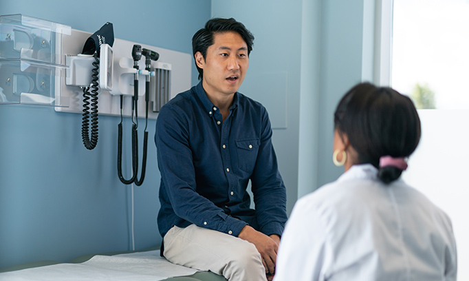 young Asian man in health exam speaking with his doctor