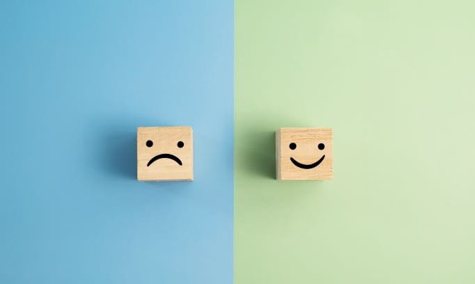 two small wooden blocks one with a smiling face and one frowning