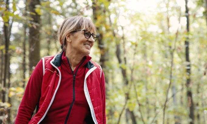 adult woman dressed in red sitting in forest of trees